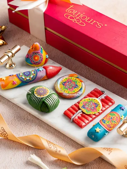 A vibrant pink box filled with my playful marzipan crackers, shaped and colored to look like traditional Diwali firecrackers. These are a fun and delicious treat, especially for families with children.