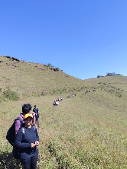 A long line of trekkers making their way up the grassy hills on the Bandaje Falls trail.