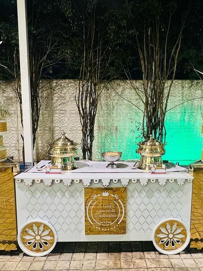 A custom-designed food cart in white and gold, part of a themed catering setup. This adds a unique and stylish element to the buffet, moving beyond standard table arrangements.
