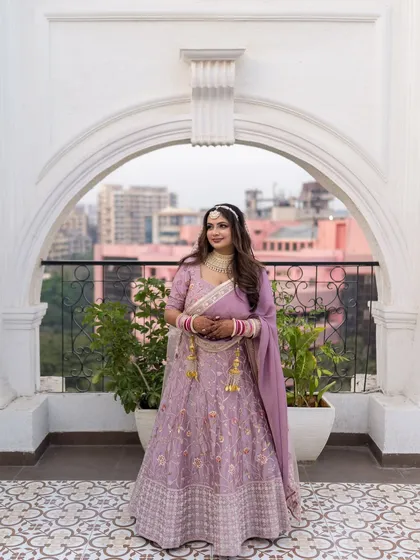 A stunning architectural portrait of the bride, Nitika, framed by a white archway that complements her elegant lehenga.