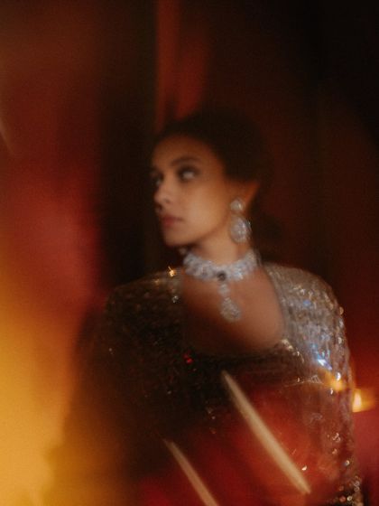 A soft-focus, dreamy portrait of the bride at her Sangeet. The warm, blurry lights create an ethereal glow around her, capturing the magic of the evening.