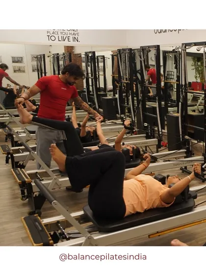 A trainer provides a hands-on assist to clients during a group class. This shows our commitment to personalized guidance, even in a group setting.
