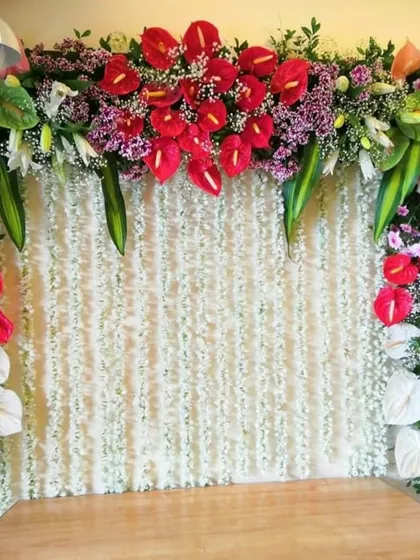 An elegant and exotic option, this backdrop combines a curtain of white flowers with a statement arrangement of tropical anthuriums.