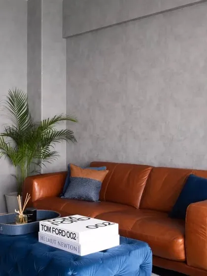 The comfortable tan leather sofa and tufted blue ottoman create an inviting atmosphere in the den, perfect for relaxing and enjoying the sea view.
