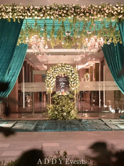 A view of the grand teal entrance from a distance, framed by foliage. This perspective shows how our entrance designs create a strong visual impact even from afar.