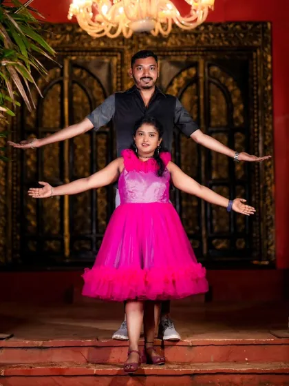A fun and grand pose in front of an ornate doorway at night. The couple's open arms create a welcoming and joyful feel.