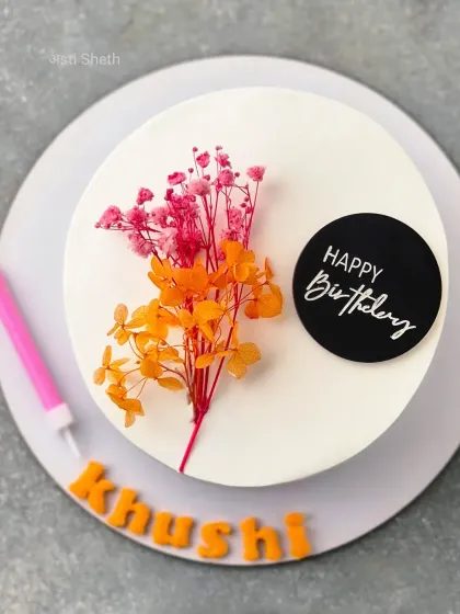 An overhead view of the minimalist Mocha Orange cake, showing the simple floral decoration and "Happy Birthday" topper.