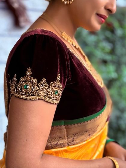 A close-up of the detailed sleeve embroidery on a client's velvet blouse. The combination of zardosi and green stones creates a look of understated opulence.