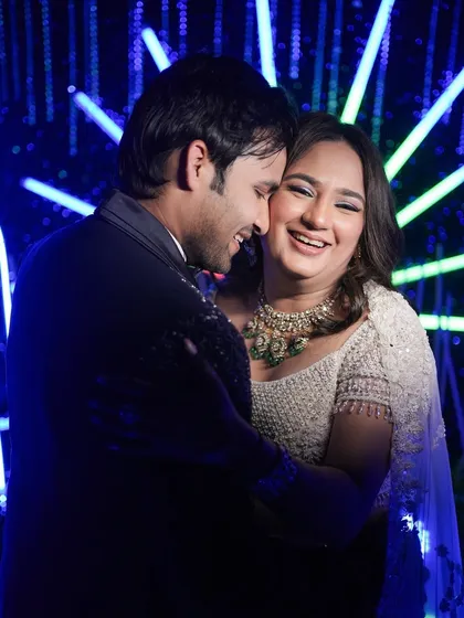 A moment of pure, uninhibited laughter during the Sangeet. The vibrant blue lights and their joyful embrace make this a standout candid shot.