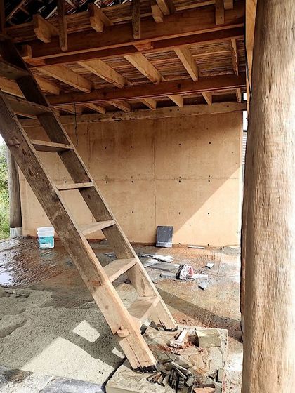 An in-progress shot of the Unnathi Farm pavilion, showing the raw timber roof structure and earthen walls before finishing.