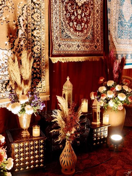 An artfully arranged corner with antique-style furniture, brass vases, pampas grass, and candlelight, adding to the warm and vintage ambiance.