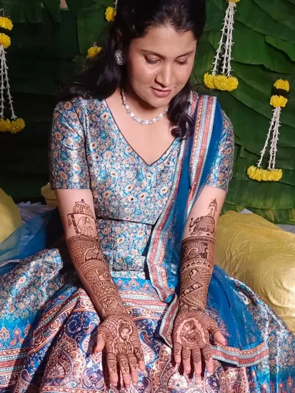 A beautiful bride in her blue lehenga, looking down at her intricate bridal mehendi. A quiet moment of admiration for the art that will be a part of her wedding day.