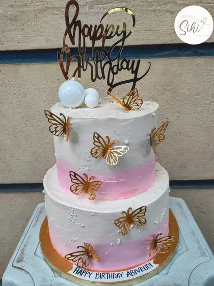 Pretty in pink and gold. This two-tier birthday cake has a soft pink ombre effect and is decorated with beautiful golden butterflies for a touch of elegance and whimsy.