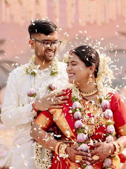An intimate and joyous moment between the bride and groom, captured amidst a shower of white flower petals.