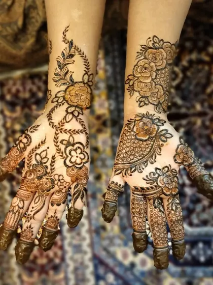 A unique floral design with two different styles on each hand. One is a dense, filled pattern, while the other is a more open and flowing vine, done for a fellow makeup artist.