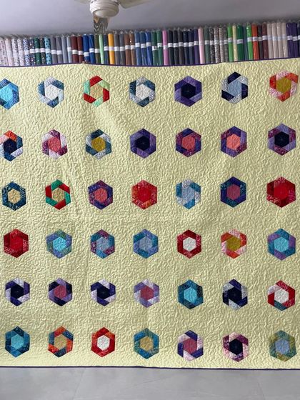 A cheerful quilt featuring colorful hexagon blocks on a pale yellow background.