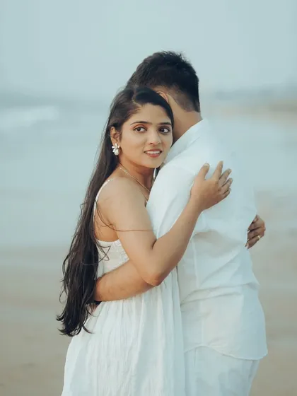 A loving embrace from behind, with a glance towards the camera. This intimate portrait on the beach captures a beautiful, candid connection.