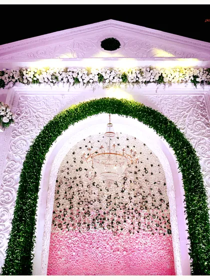 The detail of the green arch against the intricately carved white facade. This close-up shows the craftsmanship involved in creating such a grand and detailed wedding stage.