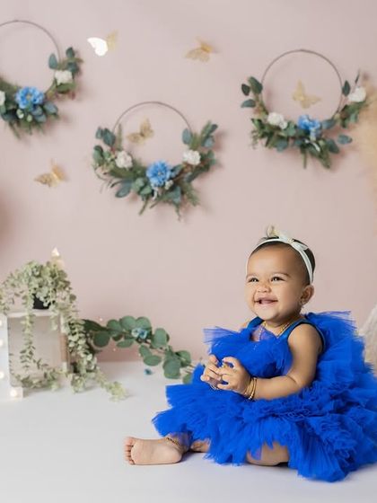 Pure, unposed bliss. Her joyful expression is the centerpiece of this first birthday portrait, complemented by a soft, celebratory backdrop.