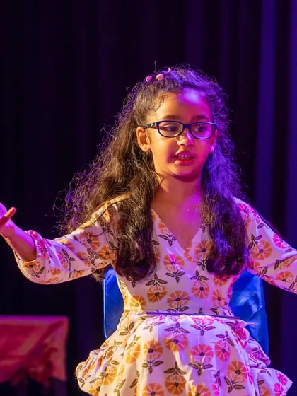 A performer seated, yet conveying strong emotion through facial expression and body language. Acting is about more than just standing and speaking.