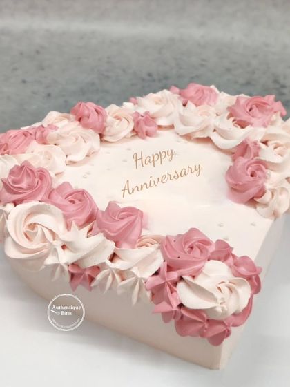 A heart-shaped anniversary cake with beautiful piping work. The two-tone pink and white roses piped around the edge give it a delicate and romantic feel, perfect for celebrating love.