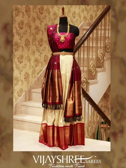 A traditional Kanjivaram half saree in classic cream and maroon. This ensemble is a perfect addition to a bridal trousseau, blending tradition with youthful elegance.
