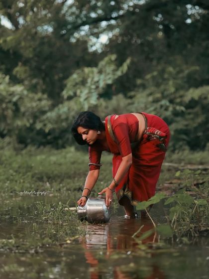 A rustic, village-themed series inspired by the movie 'Kanthara'. The model is styled in a simple red saree, captured in a natural, watery landscape to evoke a sense of raw, earthy beauty.