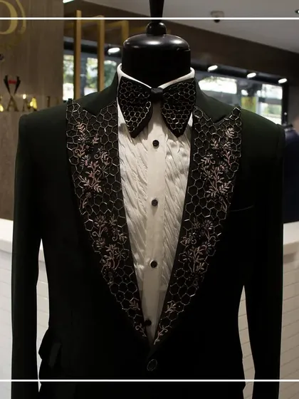 A still shot of the dark green tuxedo, highlighting the contrast between the solid green body and the intricately detailed lapels.