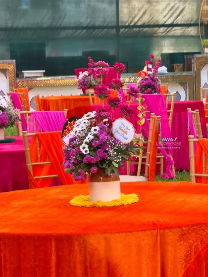 A guest table setup with a bright orange tablecloth and a beautiful floral centerpiece.