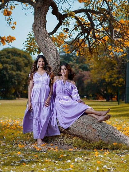 Two models in complementary lavender outfits, shot for a brand campaign. This image tells a story of friendship and shared style in a beautiful, sun-dappled park.
