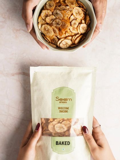 Two people share a bowl of my baked Masala Banana Chips. This top-down shot emphasizes the communal joy of sharing healthy, delicious snacks.