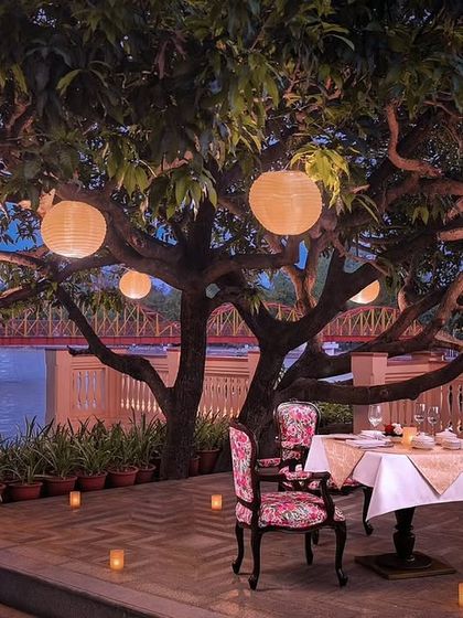 An intimate outdoor dining setting at IHCL Pilibhit-Haridwar, featuring one of our custom upholstered chairs. This image captures the magic of combining our handcrafted textiles with beautiful, natural surroundings.