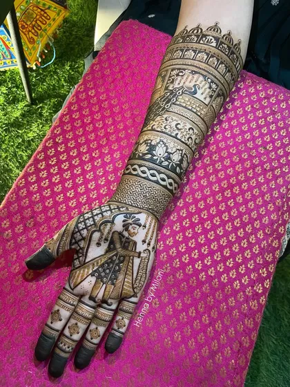 A close-up of a groom portrait on a full bridal arm. The detail in the groom's attire and the surrounding patterns is a testament to the hours of work involved.