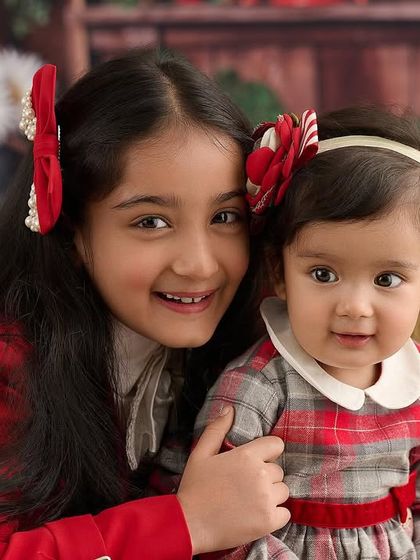 A festive portrait of two sisters in coordinated red outfits. Even with pops of color, we maintain a bright and joyful feel, perfect for holiday cards or celebrating a special occasion.