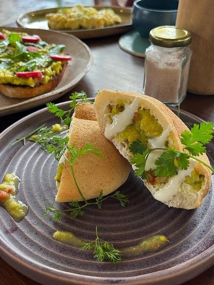 A pita pocket filled with a savory scramble. The plating is clean and modern, with fresh herbs as garnish. It looks like a light, healthy, and delicious meal.