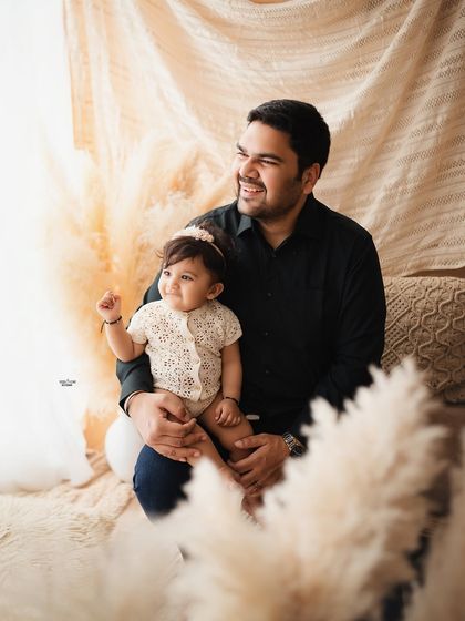 A proud papa with his adorable baby girl on his lap. A simple, sweet moment from their family photoshoot.