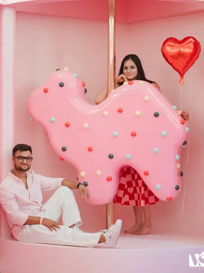 A playful and whimsical portrait on a carousel at the Museum of Ice Cream. The vibrant pinks and fun props create a lighthearted and joyful pre-wedding photo.