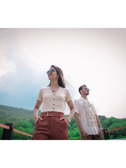 A low-angle shot of a couple looking out towards the horizon, with the bright sky and green hills creating a fresh and hopeful atmosphere.