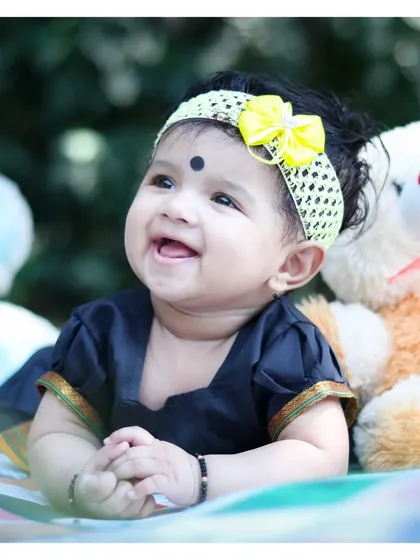 An adorable close-up from an outdoor baby milestone session. We can include different outfits, like this beautiful traditional dress, and props like teddy bears to add personality to the photos.