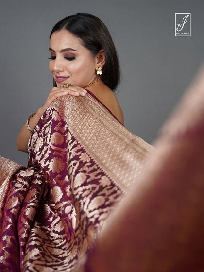 A close-up portrait capturing the model's soft expression and the fine details of the saree's border and the jewelry.