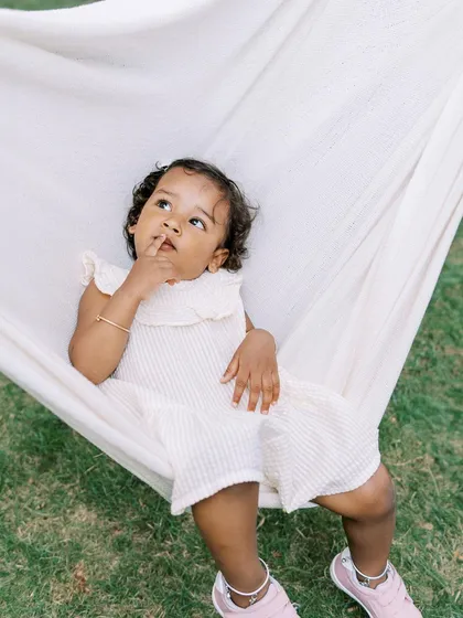 A thoughtful moment in a hammock. This two-year-old girl is lost in her own little world, creating a beautiful, candid portrait.