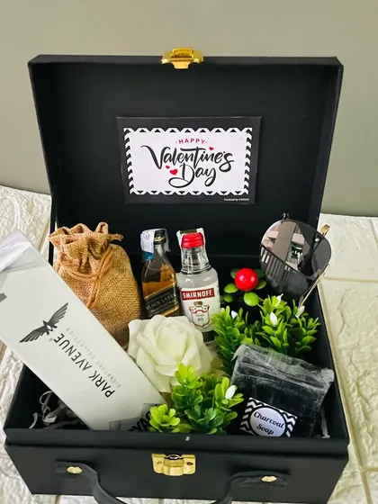 A Valentine's hamper for him in a black suitcase box. It features miniature liquor bottles, a shirt, and other curated items.