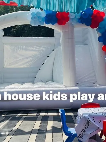 A close-up of the white bouncy with a red and blue balloon arch, ready for a festive celebration.