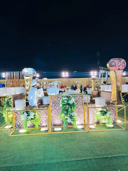 A wide shot of my gold and white counters at a nighttime event, with chefs in uniform ready to serve.