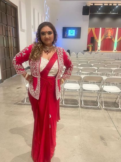 I love this Indo-Western look. My client pairs a red saree with an exquisitely embroidered jacket, accessorized with a statement necklace that perfectly complements the outfit's neckline.