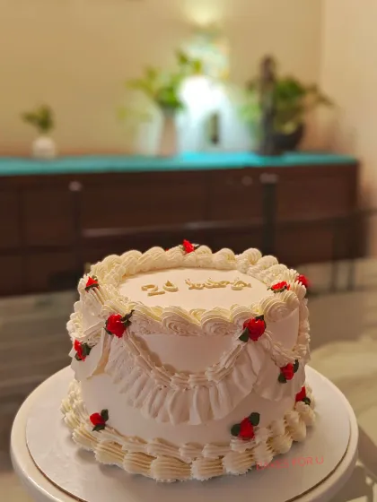 A vintage-style cake with beautiful ruffled piping in a soft cream color, decorated with tiny red roses. A classic and romantic design for any celebration.