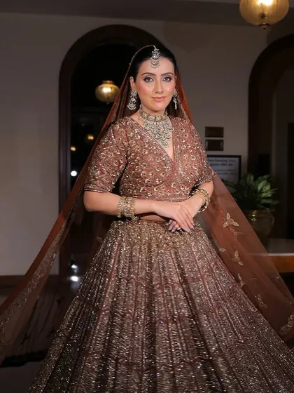 A full-length shot of the bride, her lehenga flowing around her. The jewellery adds a touch of sparkle to the grand setting.