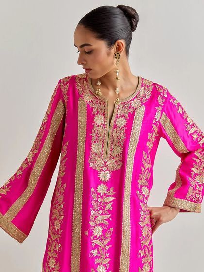 A closer look at the detailed gold floral embroidery on the fuchsia silk kurta, highlighting the craftsmanship and rich texture.