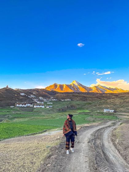 On a dirt road in Spiti Valley, with the golden hour light hitting the mountains. This image captures the raw, majestic beauty of the Himalayas and the feeling of solitary exploration.