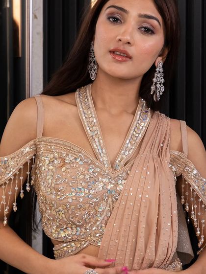 A detailed shot of the exquisite blouse on our beige draped saree gown. The combination of sequins and hanging tassels creates beautiful texture and movement.